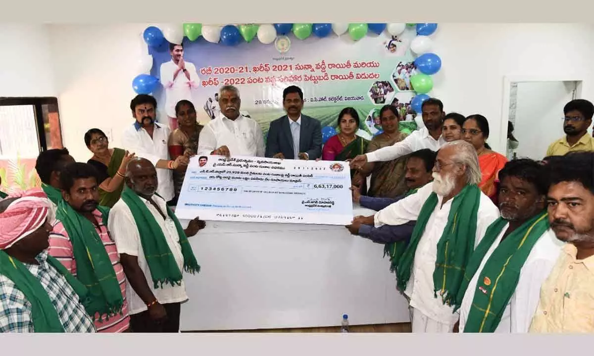 MLA Malladi Vishnu and District Collector S Dilli Rao presenting specimen cheques of input subsidy to farmers at the Collectorate in Vijayawada on Monday