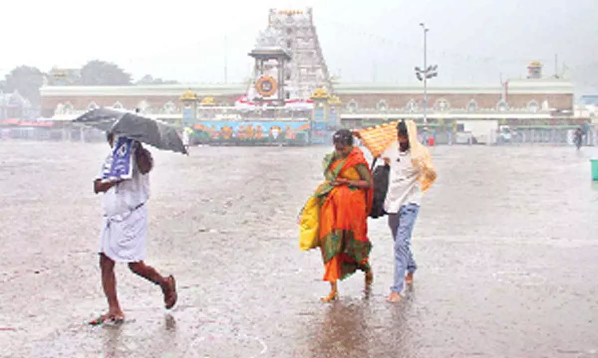Pilgrims caught unaware of rains, moving to a shelter, in Tirupati on Friday
