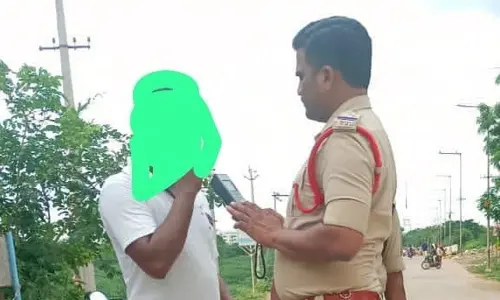 A police officer testing a bike rider with breath analyser in Prakasam district