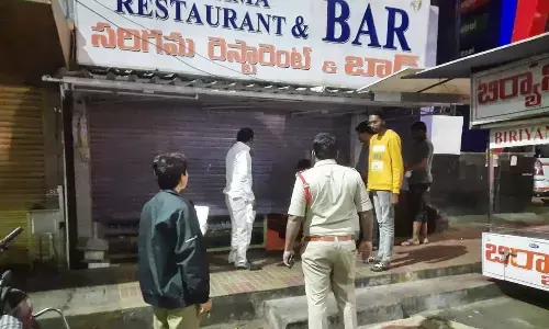 A policeman ensures that a wine shop is closed at the prescribed time in Visakhapatnam