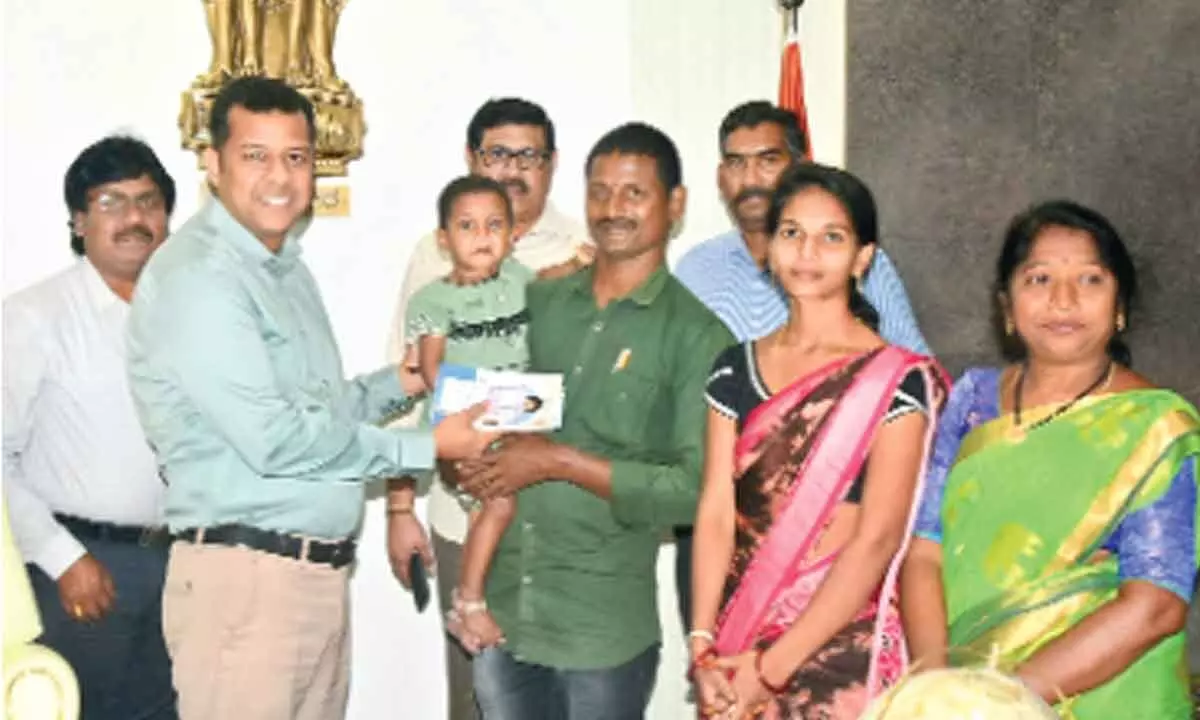 District Collector Himanshu Shukla handing over a pension of Rs 10,000 to baby Honey and her parents at Collectorate in Kakinada on Friday
