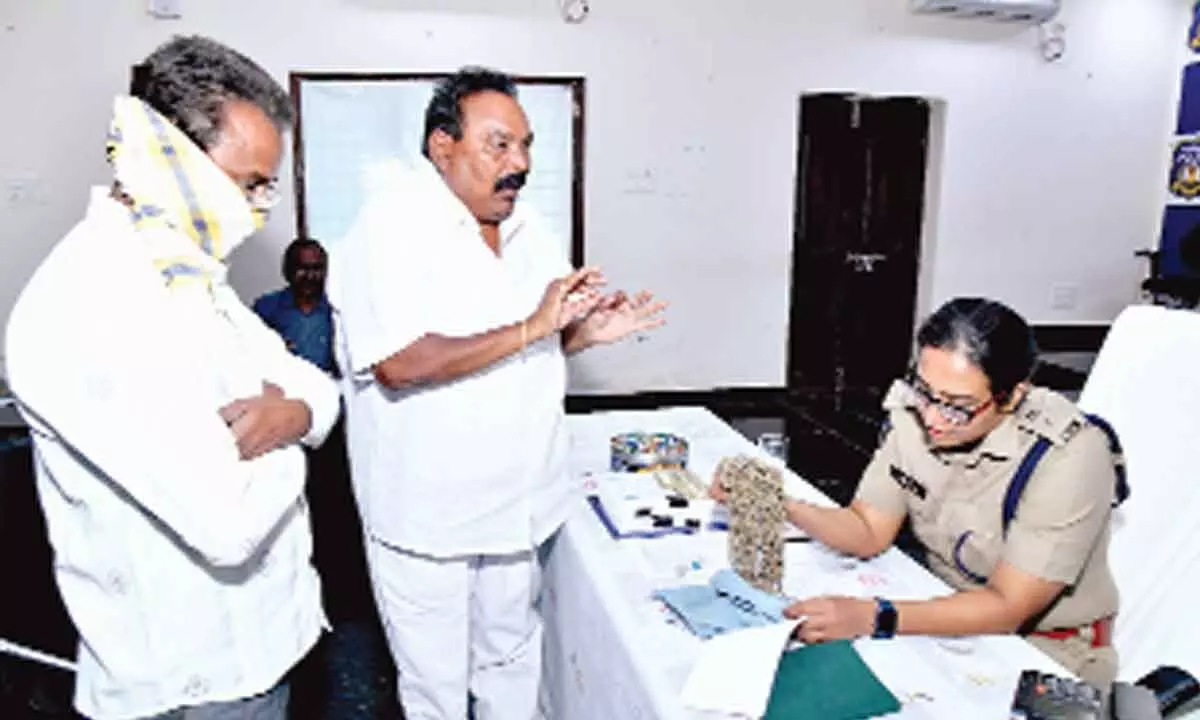 SP Malika Garg checking duplicate gold brought by a complainant at Spandana programme at DPO in Ongole on Monday