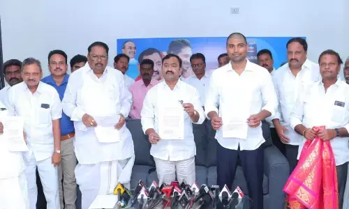 MLA Namburu Sankara Rao and MP Lavu Sri Krishnadevarayulu showing the GO for road widening works, at a press meet at MLA camp office in Guntur on Tuesday