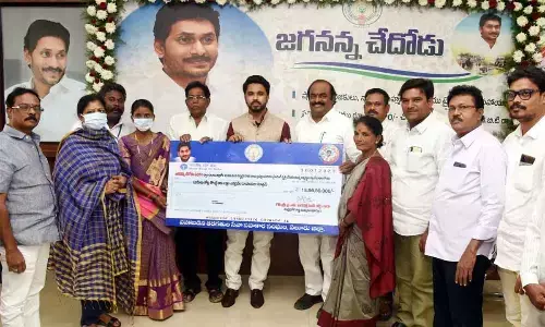 District Collector V Prasanna Venkatesh handing over a specimen cheque of financial assistance to the beneficiaries at a programme at the Collectorate in Eluru on Monday