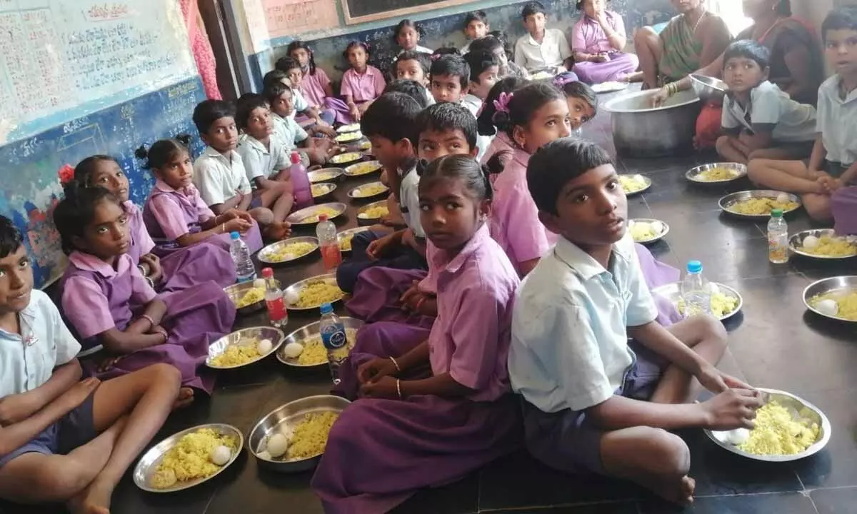 Students taking midday meals at the elementary school at Muddadapeta village in Etcherla mandal in Srikakulam district on Wednesday