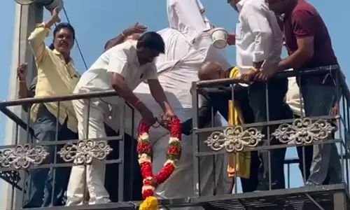 TDP leaders cleansing Tanguturi Prakasam Panthulus statue with milk, which was defiled by miscreants,  in Nellore on Tuesday