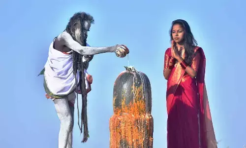 A devotee watches a sadhu performing puja to a Shivalingam at Keesaraguttaon Saturday. Photo: Adula Krishna