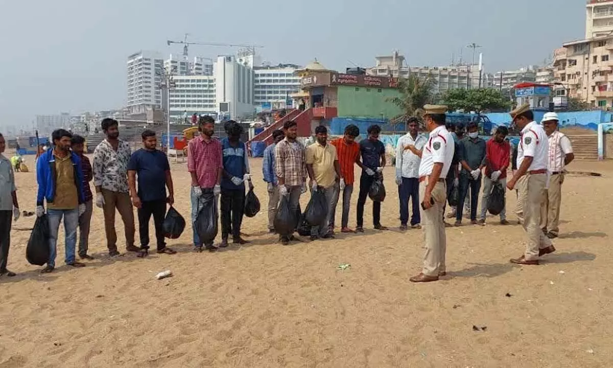 Police counselling tipplers while they undergo punishment of picking up litter at RK Beach in Visakhapatnam