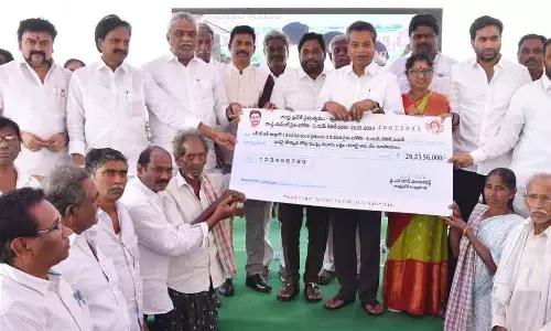 Vijayawada Central MLA Malladi Vishnu, Mylavaram MLA Vasantha Krishna Prasad and NTR district Collector Dr S Dilli Rao presenting a specimen cheque to farmers at a programme in Vijayawada on Tuesday