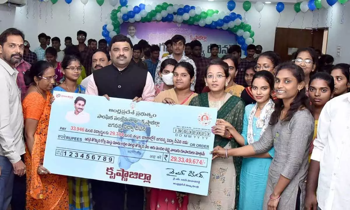 Krishna district Collector P Ranjith Basha handing over specimen cheque of Jagananna Vidya Deevana scheme to students in Machilipatnam on Sunday