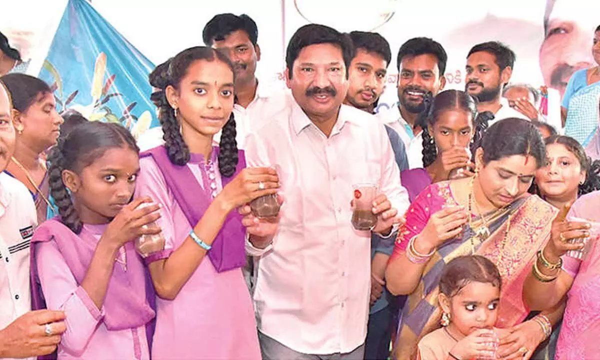 Housing Minister Jogi Ramesh distributingragi malt to students at BGK ZP High School at Pedana in Krishna district on Tuesday