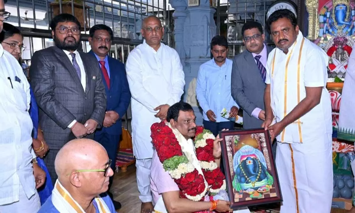 Temple Executive Officer A Venkatesh presenting the laminated photo of lord and prasadams to District Administrative Judge Cheekati Manavendranath Roy in Kanipakam temple on Sunday. District Judge E Bheema Rao is also seen.