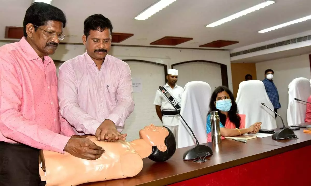 NTR district Collector S Dilli Rao and cardiac specialist  Dr K Vijay Sekhar giving a demo on heart attacks at an  awareness programme in Vijayawada on Monday