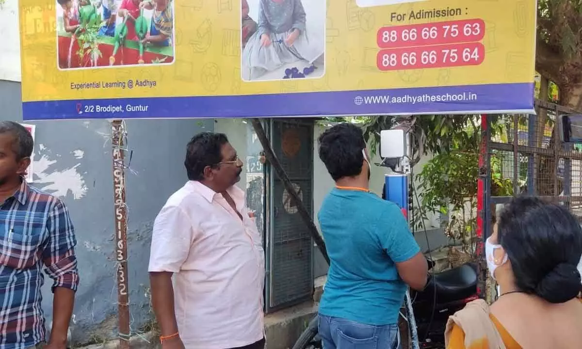 GMC town planning officials setting up QR code at a hoarding at Brodipet in Guntur on Monday