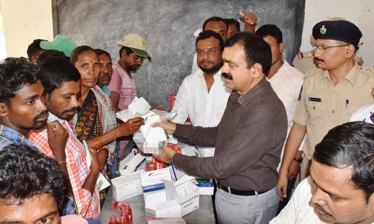 Jayashankar Bhupalpally district Superintendent of Police J Surender Reddy distributes medicines to tribals at Singaram village under Adavi Mutharam mandal in Bhupalpally district on Wednesday