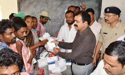 Jayashankar Bhupalpally district Superintendent of Police J Surender Reddy distributes medicines to tribals at Singaram village under Adavi Mutharam mandal in Bhupalpally district on Wednesday