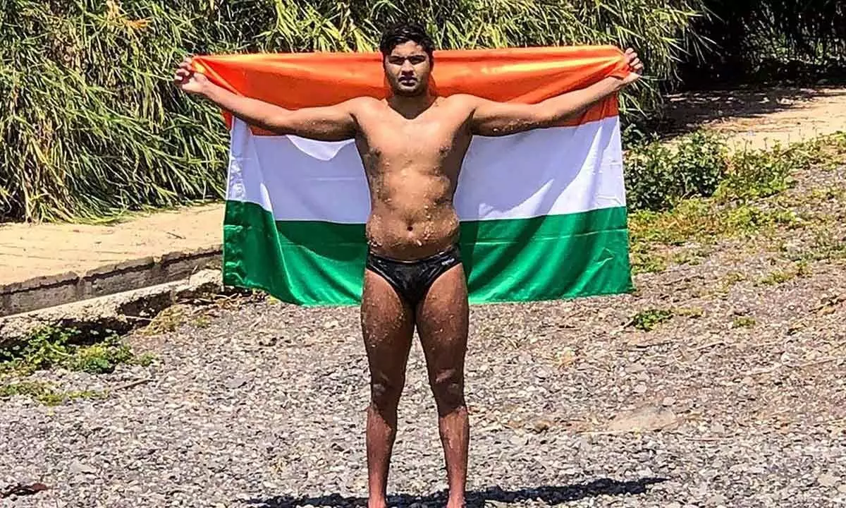 Indian swimmer, Aryan Singh Dadiala, 21, poses with the national flag as he equals the existing world record of fastest male swimmer to swim the Sea of Galilee, braving extreme weather conditions in Israel