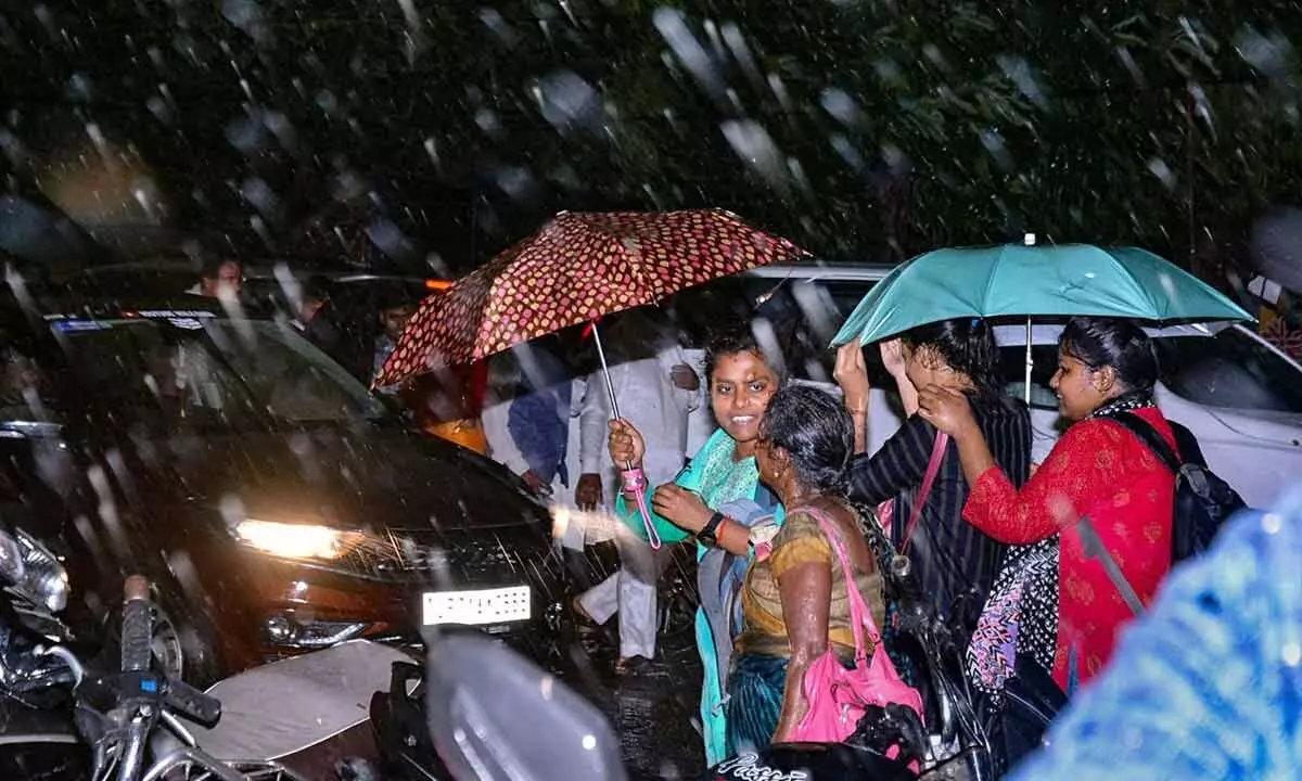 Commuters amid rainfall as dense dark clouds reduce daytime visibility, in Kanpur on Monday