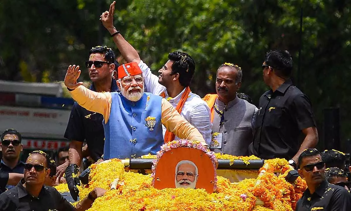 Prime Minister Narendra Modi waves at supporters and party workers during a roadshow ahead of Karnataka Assembly elections, in Bengaluru on Saturday