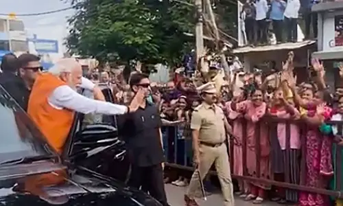 Prime Minister Narendra Modi waves at locals during his visit ahead of the Karnataka Assembly elections, in Tumakuru district on Friday