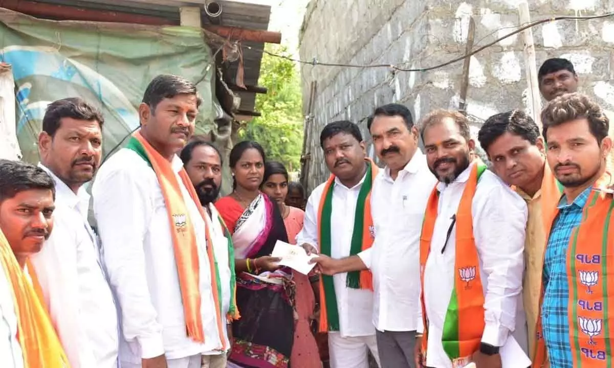 Warangal Urban Cooperative Bank chairman and BJP leader Errabelli Pradeep Rao giving away financial assistance to a woman whose tin-roof shed was damaged in Division 36 (Chintal Area) in Warangal on Tuesday