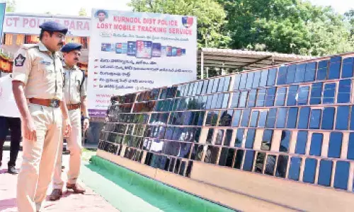 Superintendent of Police G Krishna Kanth looking at the stolen mobile phones recovered from thieves at police parade grounds in Kurnool on Saturday
