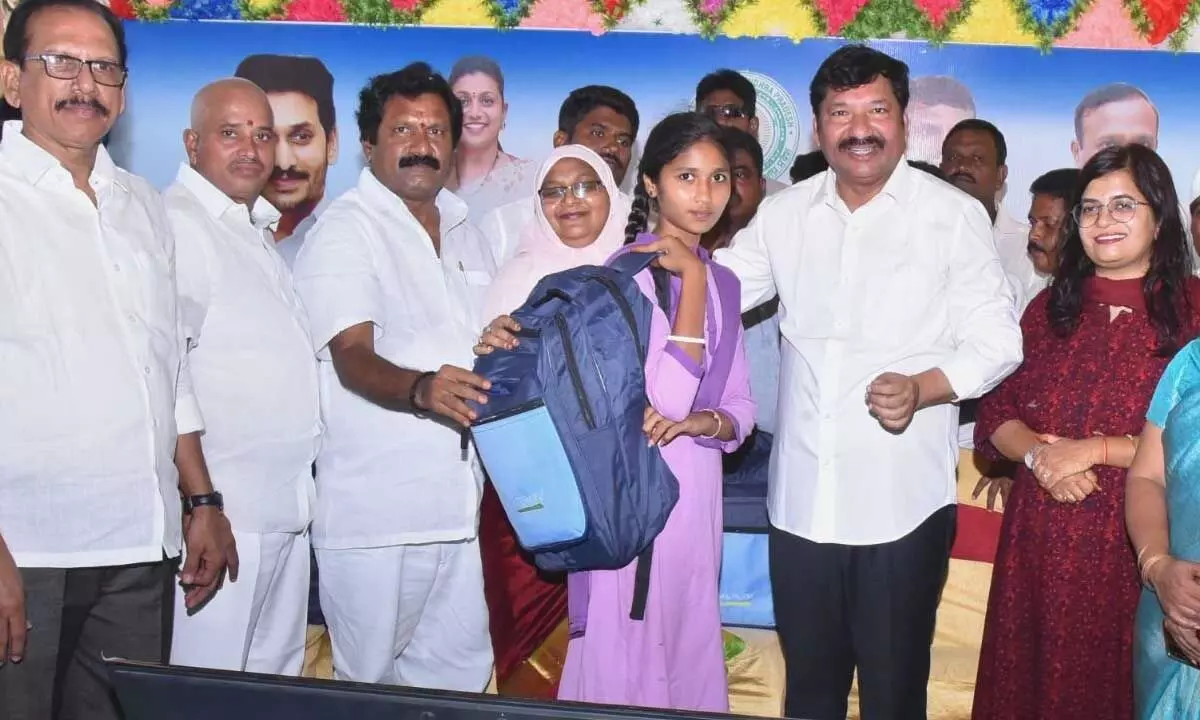 Housing Minister Jogi Ramesh handing over Vidya Kanuka kit to a student at Mallavolu village on Monday