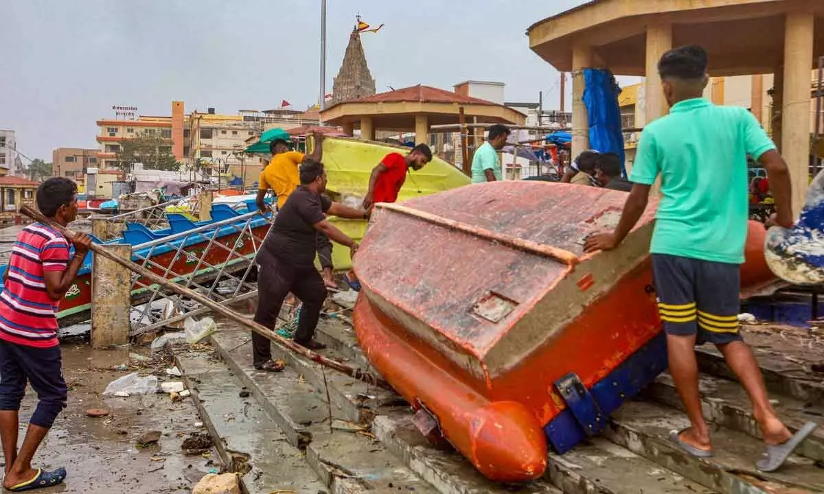 Locals anchor a boat at a ghat near Dwarkadhish temple as part of precautionary measures ahead of the landfall of Cyclone Biparjoy, in Dwarka on Thursday