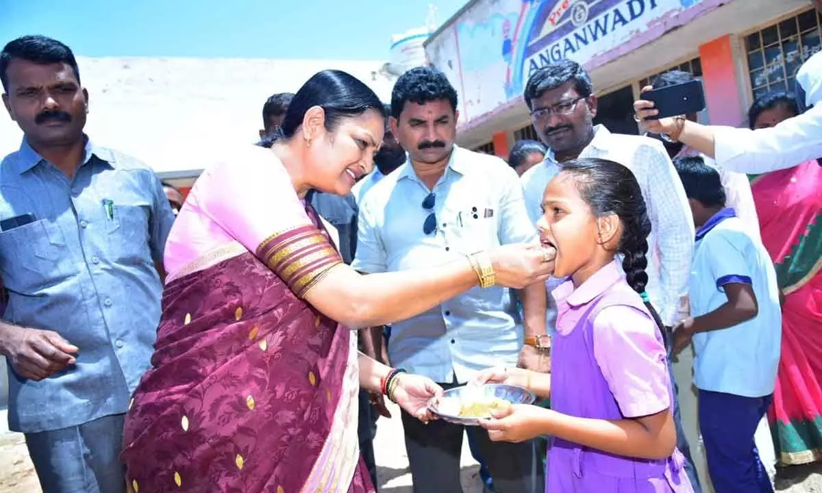 Women and Child Welfare Minister K V Ushasri Charan feeding a student at an Anganwadi centre in Yemmiganur on Thursday.
