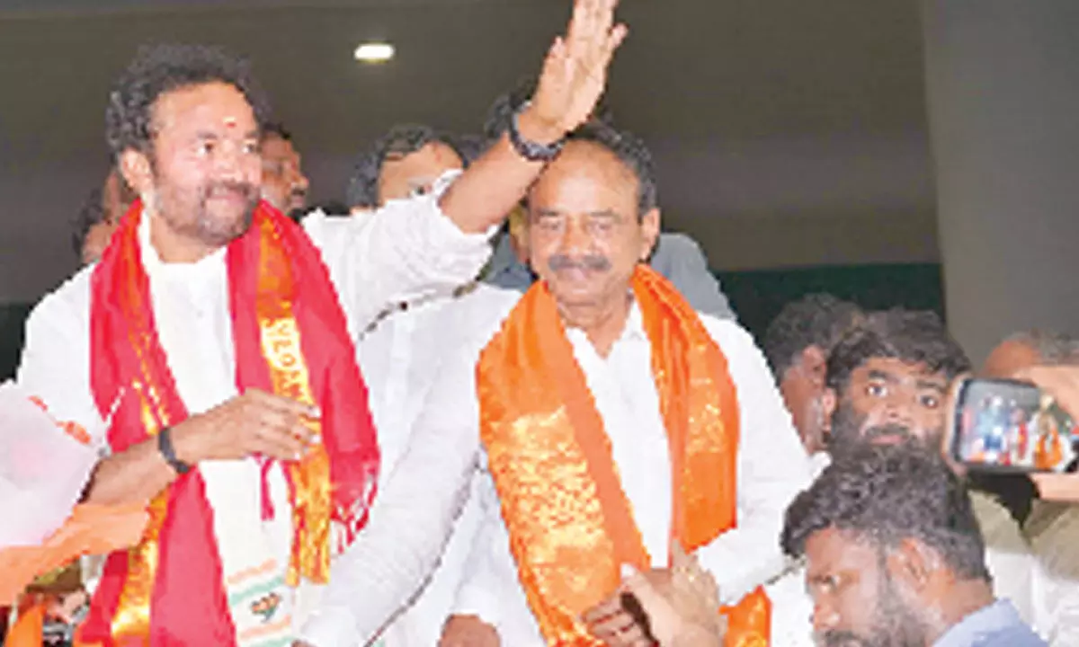 Union Minister G Kishan Reddy waving to supporters on his arrival from Delhi at he Shamshabad airport in Hyderabad on Wednesday while senior BJP leader Eatala Rajender looks on