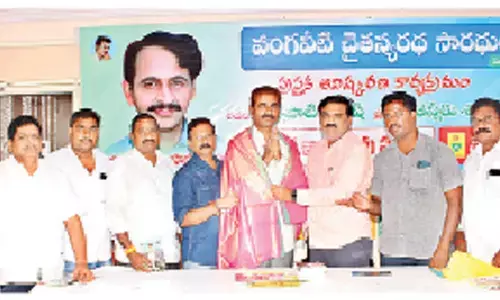 Veda Seeds executive director Tulasi Dharmacharan felicitating Turlapati Suresh, who wrote a book ‘Vangaveeti Chaitanyaratdha Saradhulu’, with a shawl at Veda Seeds office in Guntur on Monday
