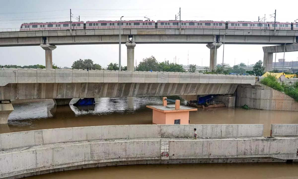 A Delhi Metro train passes above the floodwaters of the swollen Yamuna river at Mayur Vihar, in New Delhi on Wednesday