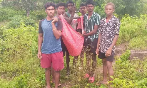 Villagers carrying a child suffering from fever in a doli in rain to Boddagummi village