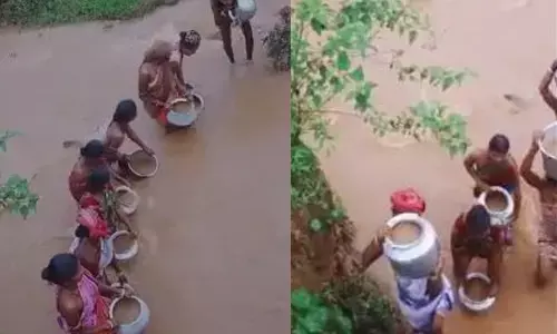 Tribal women carrying muddy water with containers in Kodagadu village of Munchangiputtu Mandal.