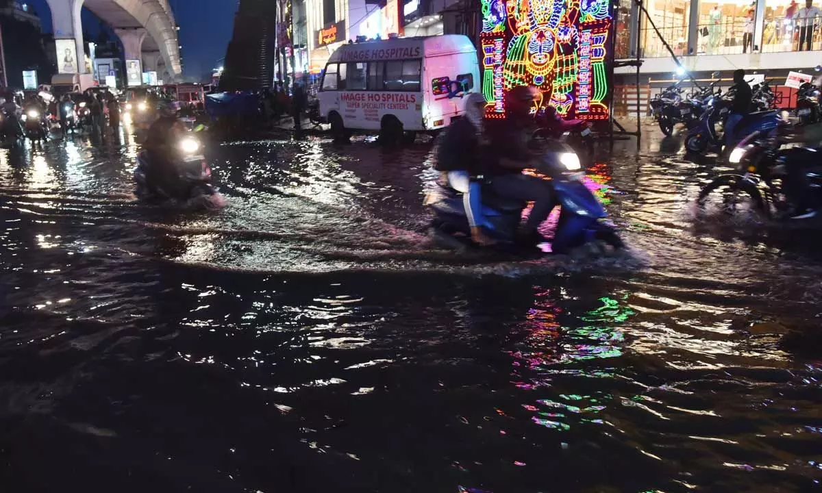 Two-wheeler riders manoeuvre cautiously on a water-logged road in Hyderabad on Monday Photo: Adula Krishna