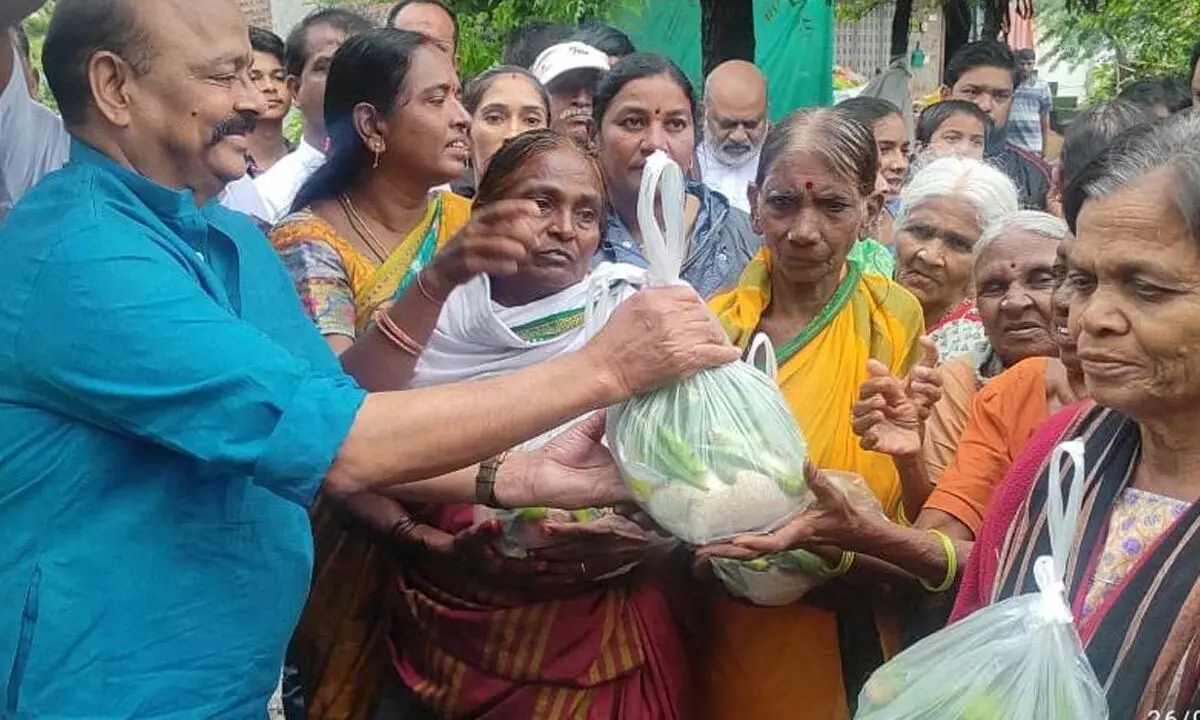 Former MLC Konda Muralidhar Rao distributing vegetables to flood-affected women in Warangal on Wednesday