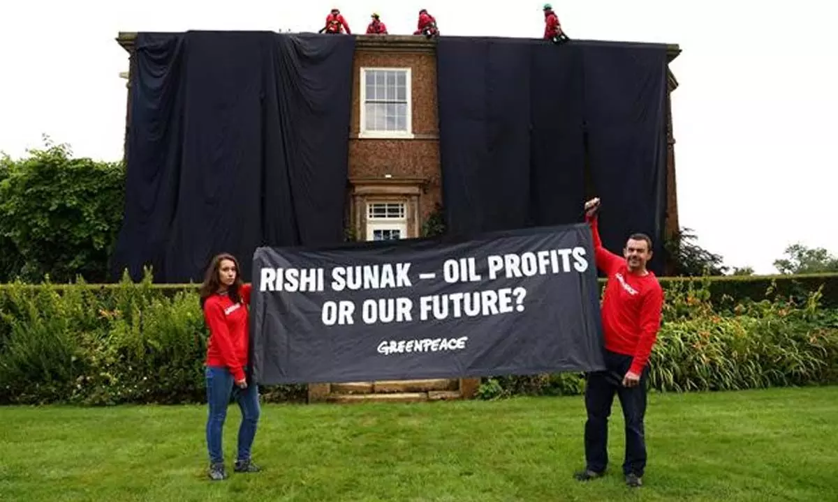Greenpeace demonstrators drape UK prime ministers house in black to protest oil expansion