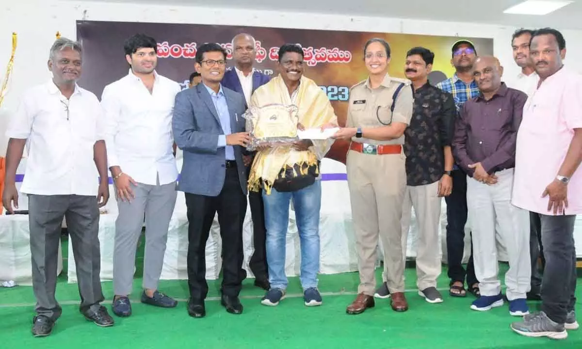 Prakasam District Collector AS Dinesh Kumar and SP Malika Garg presenting the prize and  memento to the winner of the State-level photo competition K Seetharamaiah as part of the World Photography Day celebrations in Ongole on Saturday