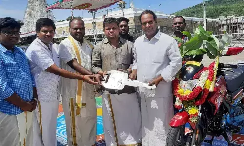 Hero MotoCorp company representative Vijay Kannan handing over key of a two-wheeler to TTD official Janakiram Reddy at Tirumala on Tuesday