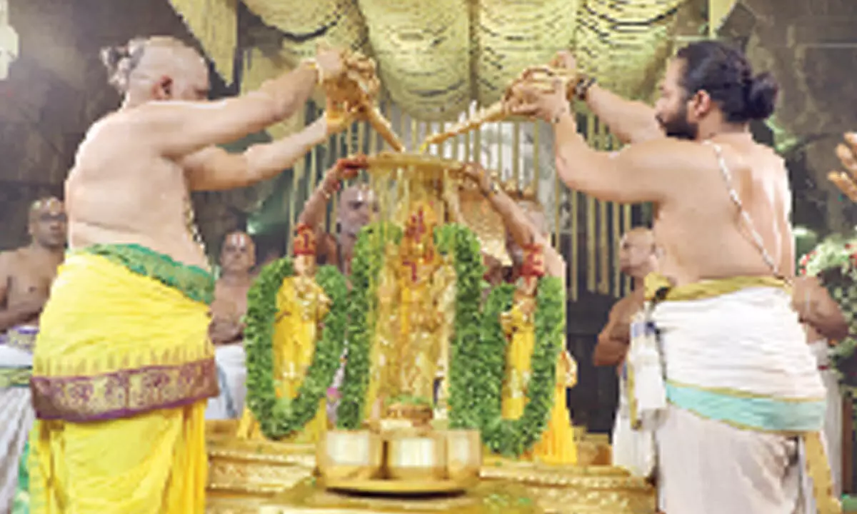 Priest performing celestial bath ‘Snapana Tirumanajanam’ to the deities at Ranganayakula Mandapam at Tirumala on Tuesday