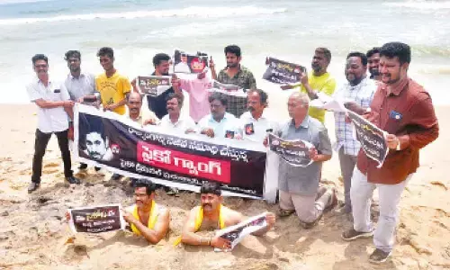 TDP leaders staging a protest by covering themselves in the beach sand at the Beach Road in Visakhapatnam on Friday