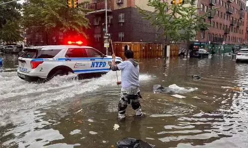 A man works to clear a drain in flood waters on Friday in the Brooklyn borough of New York. A potent rush-hour rainstorm has swamped the New York metropolitan area