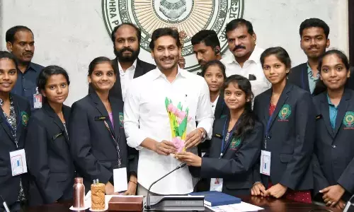 Chief Minister Y S Jagan Moha Reddy with the government school students who recently returned from US trip, at his camp office in Tadepalli on Monday