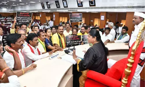 Opposition party members staging a protest displaying  placards at the Mayor’s podium in Visakhapatnam on Thursday