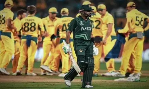 Pakistan captain Babar Azam departs as Australian team members gather around at Chinnaswamy Stadium, Bengaluru, during the match held on Friday