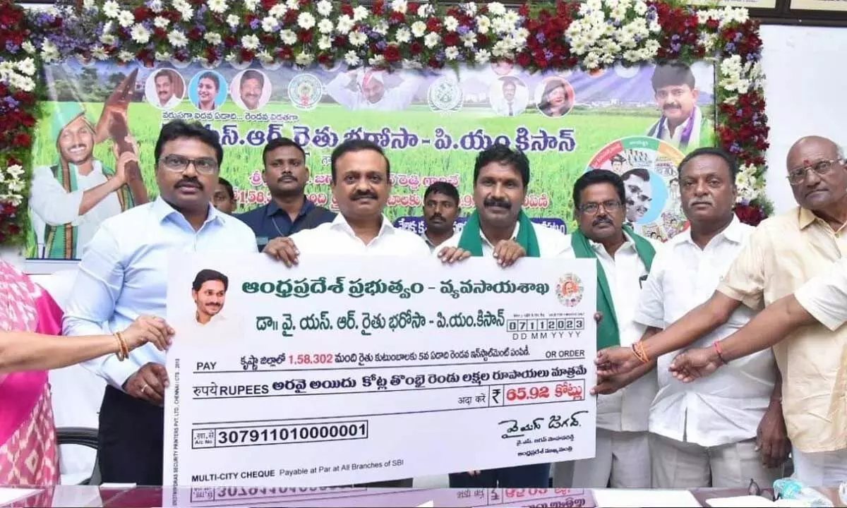Machilipatnam MP V Balashowry and collector P Rajababu handing over cheque to farmers in Machilipatnam on Tuesday