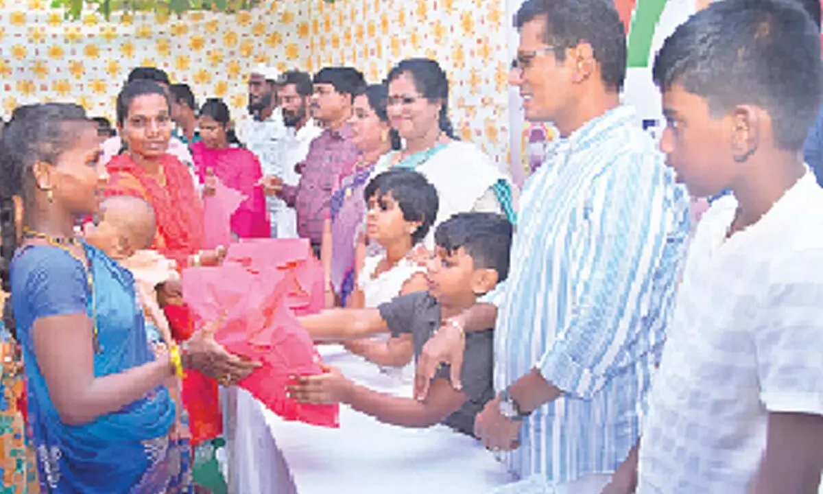 Prakasam district Collector AS Dinesh Kumar and his family members distributing clothes, sweets and crackers to people in Ongole on Monday
