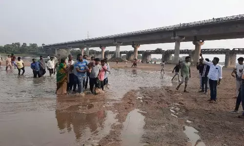 Local people rescucing a person from Munneru river at Keesara in NTR district on Monday