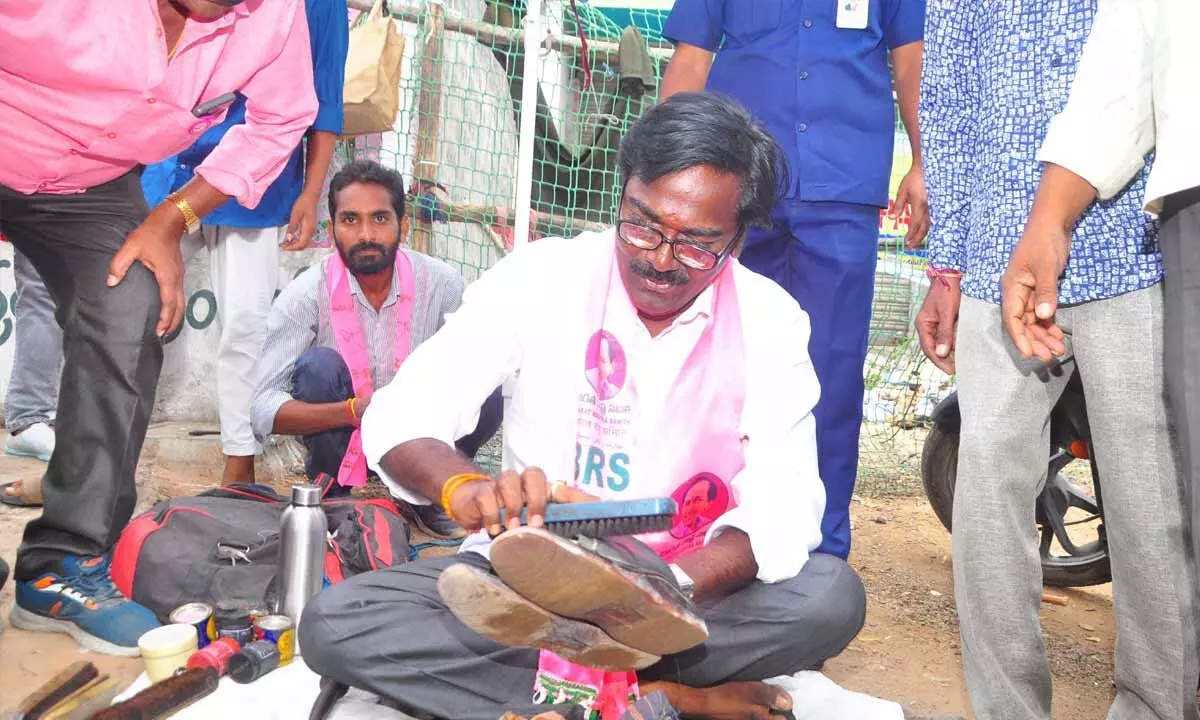 BRS candidate for Khammam Assembly and Minister Puvvada Ajay Kumar polishing chappals at a shop during his campaign in Khammam on Wednesday