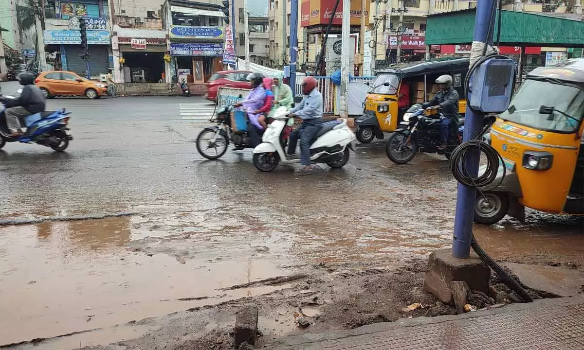 Commuters wore raincoats to commute on rainwater filled roads in Visakhapatnam on Monday.